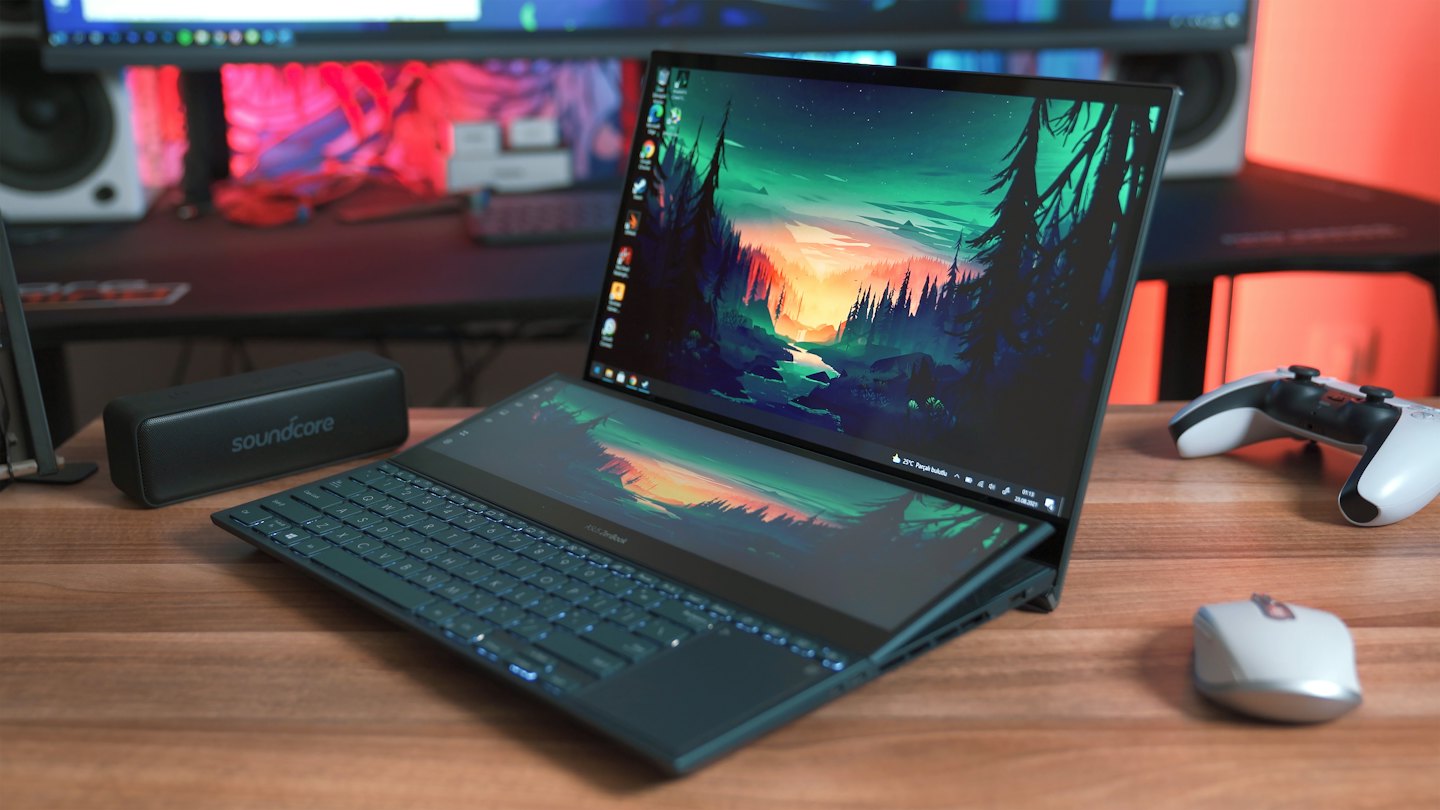 Dual-screen laptop displays landscape wallpaper on a wooden desk.